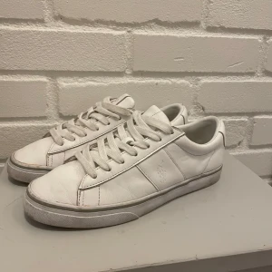 Vita sneakers från Polo - Säljer ett par klassiska vita sneakers från Polo i mycket bra skick. De har en stilren design med snörning och är perfekta för vardagsbruk. Skorna är gjorda i skinn och har en bekväm passform.