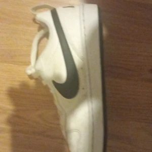 Vita Nike sneakers med svart swoosh - Säljer ett par klassiska vita Nike sneakers med svart swoosh. De har snörning och är i bra skick, perfekta för vardagsbruk. Skorna är ren  och passar till det mesta. Perfekta för både vår och sommar. Tar swish!