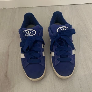Blå Adidas Campus sneakers - Säljer mina asfeta adidas campus som är i mycket bra skick. Enbart använda fåtal gånger detta året. Kände dock att det inte riktigt passar min stil så säljer dem nu då någon annan får mer användning för dem än mig tror jag. Tillkommer också 2 extra snören som aldrig används (vita och smalare i blå färg)