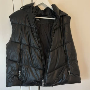 Svart quiltad väst från Zara - Säljer en snygg svart quiltad väst från Zara i storlek M. Västen har en dragkedja framtill och två praktiska fickor med dragkedjor. Perfekt för höst och vår när du vill hålla dig varm men ändå se stilren ut. Passar både till vardags och lite mer uppklädda tillfällen.