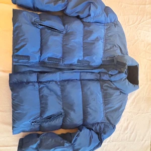 Blå gantjacka - Säljer en jättefin och mysig vinterjacka från gant. Den har dragkedja upp hela vägen. Har en liten krage som värmer runt halsen. Har två fickor på magen.