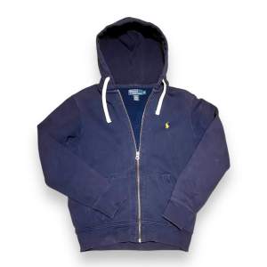 Säljer en Ralph Lauren zip-up hoodie i nyskick! Supermjuk och bekväm, perfekt både till vardags och för att klä upp en avslappnad look. Klassisk design med den lilla broderade Polo-loggan på bröstet.