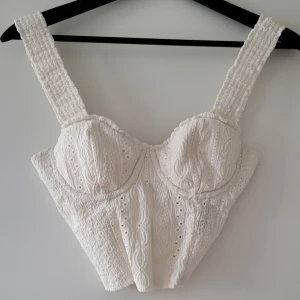 Vit korsettopp från NA-KD - Säljer en superfin vit korsettopp från NA-KD i storlek XS. Toppen har ett vackert broderat mönster och breda axelband. Har bygel vid bysten. Använd fåtal gånger men i bra skick. 