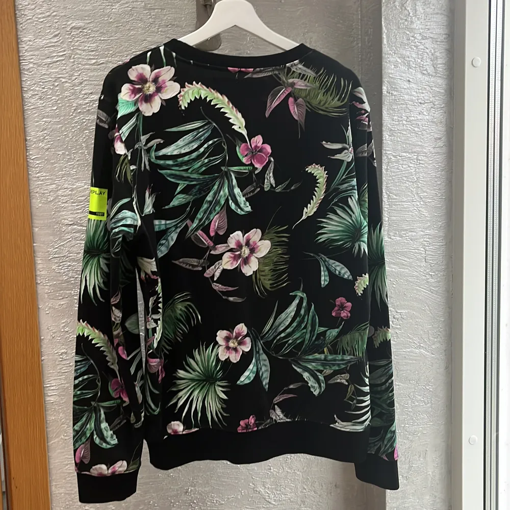 Säljer en snygg svart tröja från Replay med ett tropiskt blommönster i grönt och rosa. Tröjan har långa ärmar och är perfekt för att liva upp garderoben. Den är i mycket bra skick och passar perfekt för både vardag och fest. Nypris ca 1500kr. Neuletakit & Villapaidat.