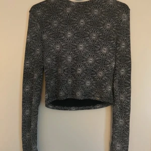 Glittrig tröja  - Säljer en superfin croppad topp med ett coolt geometriskt mönster i glitter, Den är långärmad och perfekt för både vardag och fest. Toppen är tight och framhäver figuren snyggt. Passar perfekt till ett par höga jeans eller kjol!