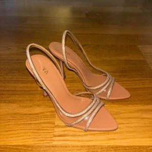 Beige klackskor från Zara - Snygga beige klackskor från Zara med spetsig tå och smala remmar. Perfekta för festliga tillfällen! De har en elegant design med en bekväm passform. Använd dem för att lyfta din outfit till nästa nivå.