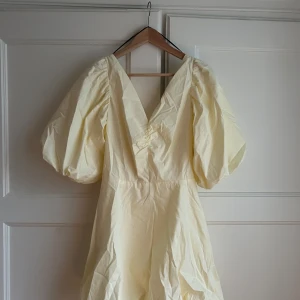 Ljusgul klänning med puffärmar - Säljer en superfin ljusgul klänning med puffiga ärmar och v-ringning. Den har en söt rosett knytning i ryggen 💛 aldrig använt!