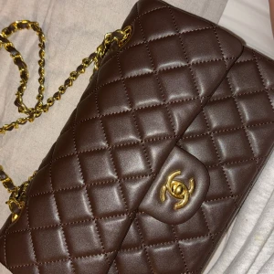 Brun quiltad axelväska - Säljer en superfin brun quiltad axelväska i skinn med gulddetaljer. Fyndade den på märkes secondhand i Köpenhamn, mer info har jag inte angående själva väskan, en har en klassisk design med en snygg kedja och ett elegant spänne framtill. Perfekt för både vardag och fest, super snygg höst väska, stor och rimlig 