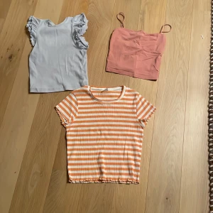 Tre toppar i olika stilar - Det är en ljusblå topp med volanger från Kappahl som är storlek 146/152 men är liten i storleken, ett rosa linne från Gina tricot i storlek XS som är en mag tröja och en orange och vit randig tröja från Lindex i storlek 158/166 också liten i storleken.🧡🩵🩷