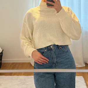 ibbad polotröja - Säljer en supermysig beige polotröja i ribbat material, cremevit färg. Den är croppad och har en loose passform som är perfekt för både höst och vinter. Tröjan har långa ärmar och en hög krage som håller dig varm. Perfekt att matcha med jeans för en avslappnad look!