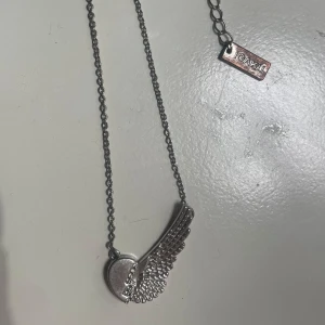 Ioaku halsband med vinge - Snyggt silverfärgat halsband med  vinge. Perfekt för att ge din outfit en unik touch. 
