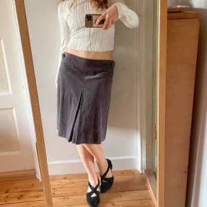 Grå manchester kjol med knappar - Säljer en stilren grå kjol i mycket bra skick. Kjolen har en elegant slits framtill och dekorativa knappar i midjan. Perfekt för både vardag och festliga tillfällen. Passar bra till höst- och vårgarderoben!