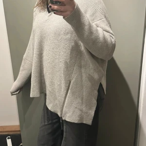 Beige stickad tröja från AllSaints - Säljer en supermysig grå stickad tröja från AllSaints i storlek L. Den har en v-ringad design och långa ärmar, perfekt för kyliga dagar. Materialet är en blandning av ull och nylon, vilket gör den både varm och bekväm. Perfekt för höst och vinter! 🍂❄️