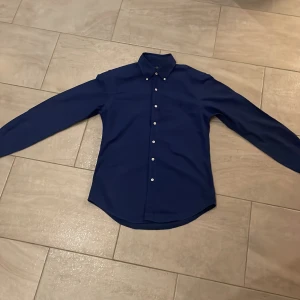 Blå skjorta från Ralph Lauren - Säljer en snygg blå skjorta från Ralph Lauren i slim fit M som passar mer S. Skjortan har långa ärmar och knappar fram. Perfekt för både vardag och fest! 💙