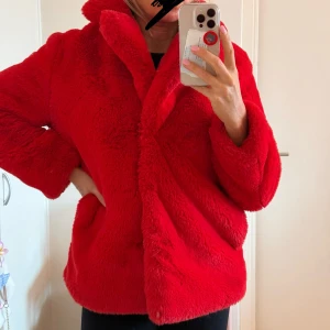 Röd teddyjacka från Gina Tricot - Superfin röd teddyjacka från Gina Tricot i storlek 34. Den är perfekt för höst och vinter med sitt mjuka och fluffiga material. Jackan har långa ärmar och stängs med knappar. Den är i nytt skick och kommer med extra knappar. Perfekt för att hålla sig varm och snygg!