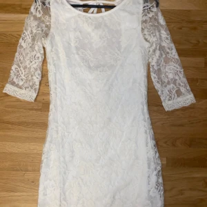 Vit trekvarts studentklänning - Säljer en superfin vit spetsklänning med trekvartsärm och öppen rygg. Klänningen har en tight passform och knytning i ryggen för extra detalj. Perfekt för sommarens fester eller studentfirande! 🌸