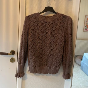 Brun stickad tröja från Lindex - Säljer en superfin brun/bronzig stickad tröja från Lindex i storlek S. Den har ett snyggt mönster och långa ärmar med ribbade muddar. Perfekt för höst och vinter när du vill vara både varm och stilren. 🧶