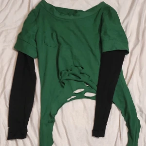 Yogi from Carneval cosplay tröja - DETTA ÄR EN SYDD COSPLAY TRÖJA. MEN KAN ANVÄNDAS SOM VANLIGA KLÄDER.Unik grön och svart tröja med coola slitningar och lager-på-lager-look. Perfekt för en edgy stil. Den gröna delen är kortärmad och den svarta delen är långärmad. Passar bra till både vardag och fest.