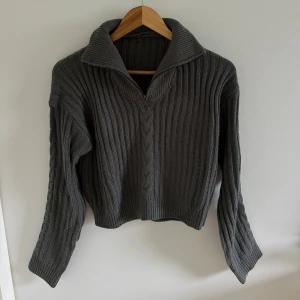 Grå stickad tröja med dragkedja - Säljer en varm grå stickad tröja med dragkedja framtill. Den har en hög krage, är ribbad och har långa ärmar. Använd endast två gånger.