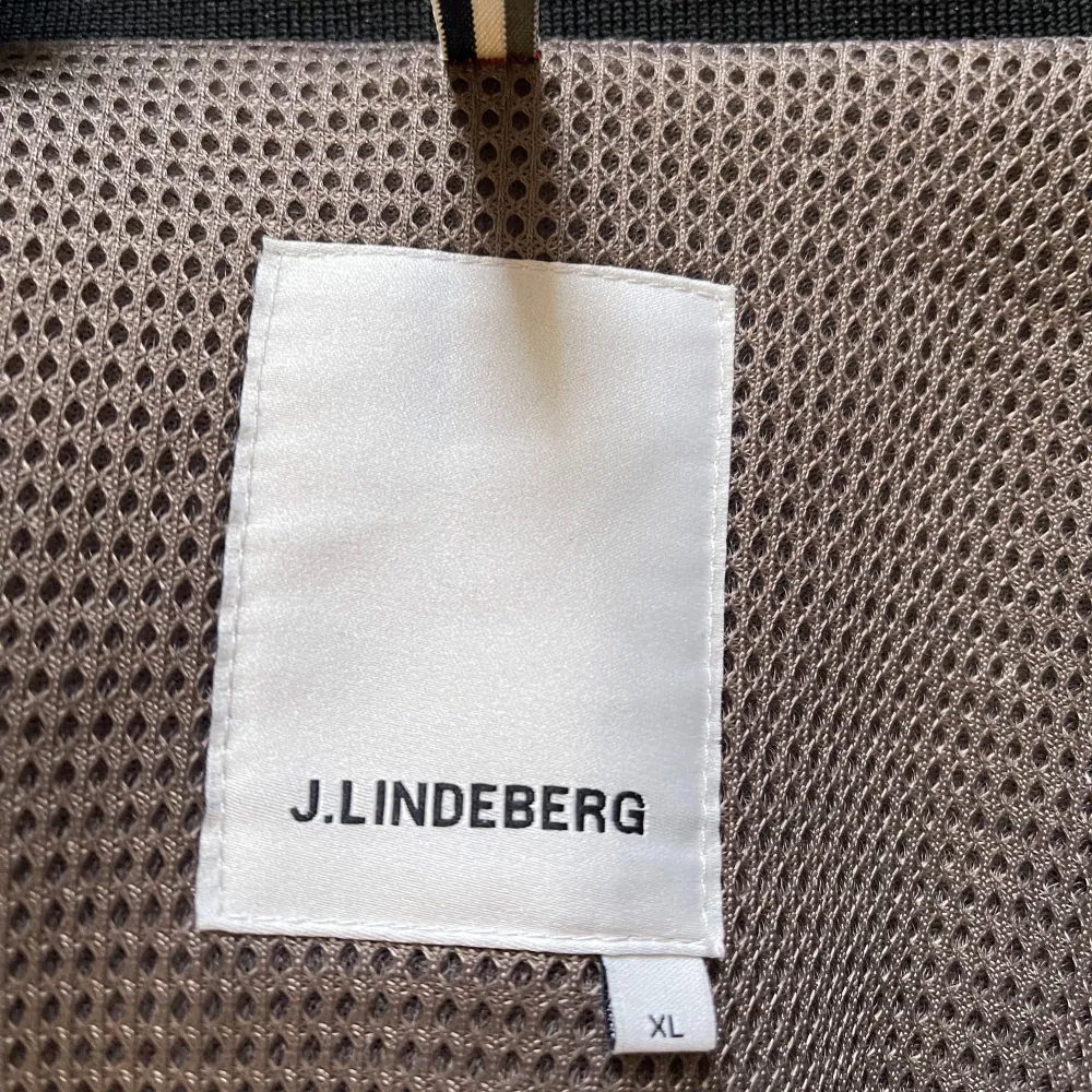 Säljer en snygg svart jacka från J.Lindeberg i storlek L/XL. Jackan är tillverkad i 100% polyester och har en stilren design med dragkedja och knappar. Perfekt för höst och vår med sina praktiska fickor och bekväma passform.Ny pris 3400.  För mer information dm✉️. Jackor.