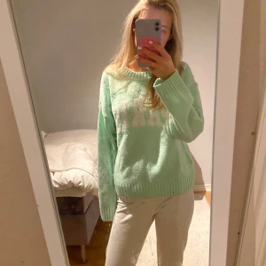 Mintgrön stickad tröja med text - Säljer en superfin mintgrön stickad tröja med texten 'PARIS' i vitt på framsidan. Tröjan har långa ärmar och ribbade muddar vid ärmslut och nederkant. Perfekt för en mysig dag hemma eller en promenad i stan. Passar bra till både jeans och kjol!