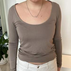 Säljer en stilren beige långärmad topp i mjukt material. Den har en djup rundad halsringning och en tight passform som framhäver figuren. Perfekt för både vardag och festliga tillfällen. Passar bra till jeans eller kjol!