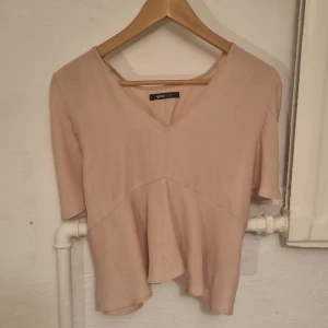 Beige topp från Gina Tricot - Säljer en rosa/beige topp från Gina Tricot. Den är v-ringad och korta ärmar. Storlek S och i bra skick.