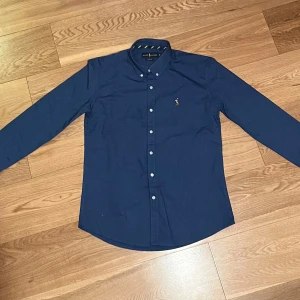 Skjorta från Ralph Lauren - Säljer en mörkblå skjorta från ralph lauren i storlek M. Fick den i present ett tag sedan men har inte använts så mycket då den inte passar mig, därav väldigt fint skick. Kolla gärna mina andra annonser!