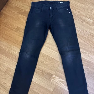 Replay Anbass jeans - Snygga svarta jeansbyxor från Replay med en klassisk femficksdesign. Byxorna har en slim passform och är perfekta för en stilren look. De är tillverkade i ett bekvämt material som ger en skön känsla hela dagen. W30 L32