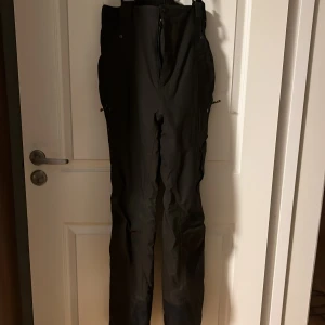 Gröna byxor från McKinley str M - Säljer ett par gröna termobyxor från McKinley med praktiska fickor och dragkedja. Perfekta för utomhusaktiviteter med robust design och bekväm passform.