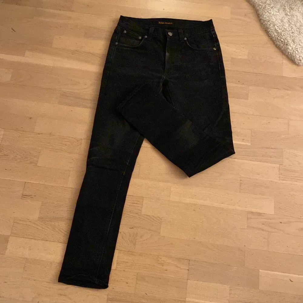 Snygga svarta jeans från Nudie Jeans med klassisk femficksdesign. De har en slim passform och är tillverkade i ett slitstarkt denimtyg. Perfekta för en stilren look. De passar någon som är ca 174 cm lång och modellen är Lean dean som sitter slim. Ny pris ca 1700kr- mitt pris 375 men kan gå ner i pris till 325 i snabb affär!!!. Farkut & Housut.