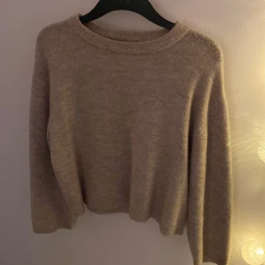 Beige stickad tröja - Mysig beige stickad tröja med rund hals och långa ärmar. Perfekt för kyliga dagar och enkel att matcha med olika outfits.