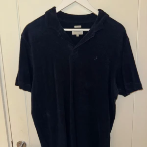 Mörkblå pikétröja från Boomerang - Säljer en stilren mörkblå pikétröja från Boomerang, stickad i Sverige. Tröjan har korta ärmar och en klassisk krage. Perfekt för en avslappnad look. Material är typ som handduks material riktigt snyggt.   Storlek: M  Färg: Mörkblå Nypris: ~1300kr  Använd Max 3 gånger