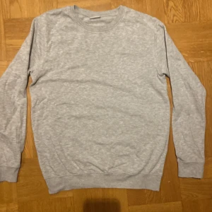 Grå tröja från Kappahl - Säljer en enkel och stilren grå tröja från Kappahl. Tröjan har långa ärmar och en rund halsringning, perfekt för en avslappnad look. Passar bra till både jeans och mjukisbyxor.