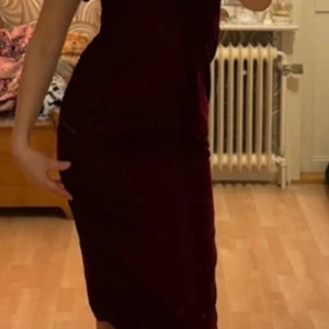 Vinröd sammets klänning från Hope & Ivy - Säljer en elegant vinröd klänning från Hope & Ivy. Klänningen har en offshoulder-design med volangdetaljer upptill. Perfekt för en stilfull kväll.