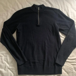 Mörkblå half zip stickad tröja  - Säljer en stilren mörkblå tröja från Jack & Jones med halv dragkedja. Perfekt för kyligare dagar med sin ribbade struktur och långa ärmar. Enkel att matcha med olika outfits.