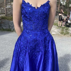 Blå lång balklänning med spetsdetaljer - Superfin balklänning som jag bar förra året. Sitter jättebra och lätt att justera med knytningen baktill. Med mina 170cm och en klack på 5cm, nuddade den marken precis. Nypris 2600, kom med prisförslag!🤩💗