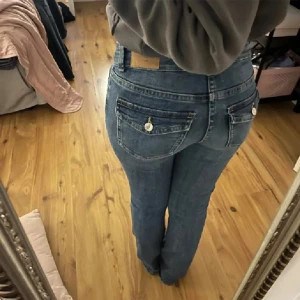 Blå jeans med knappar - Säljer ett par klassiska blå jeans med knappdetaljer på bakfickorna. De har en normal passform och är perfekta för vardagsbruk. Skriv för frågor!💓pris går att diskutera vid snabb affär 