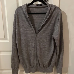 Merinoull zip Hoodie  - Säljer en stilren grå hoodie från MNG i mjuk merinoull. Tröjan har dragkedja framtill och en bekväm huva. Perfekt för kyliga dagar. Tröjan är i storlek M. 🙌🙌😁🤝
