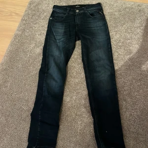 Mörkblå jeans från Replay - Snygga mörkblå jeans från Replay med klassisk femficksdesign och knappgylf. Perfekta för en stilren look. Märkesdetaljer på fickan och baksidan av midjan. Använda några gånger