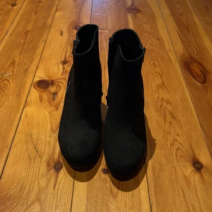 Svarta mocka boots med kilklack - Snygga svarta boots i mocka med kilklack och dragkedja på sidan. Perfekta för både höst och vinter. Stilrena och enkla att matcha med olika outfits.