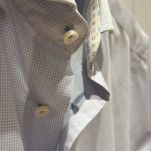 Rutig skjorta från Riley - Snygg rutig skjorta från Riley i slim fit. Skjortan har ett diskret rutmönster i blått och vitt med kontrasterande blommigt mönster på insidan av kragen och manschetterna.