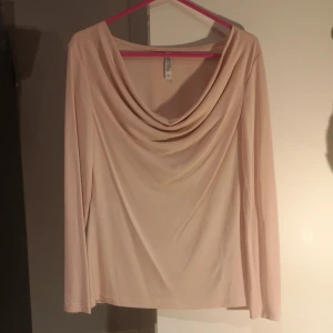 Ljus rosa topp från Chiara Forthi - Säljer en elegant ljus rosa topp från Chiara Forthi med draperad halsringning. Toppen har långa ärmar och är tillverkad i ett mjukt material som ger en skön passform. Perfekt för en stilren look.