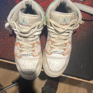 Nike Air Jordans med turkos sula - Säljer ett par vita Nike Air Jordans med turkos sula och orange detaljer. Skorna har snörning och perforeringar på ovansidan för bättre ventilation. Perfekta för dig som vill ha en stilren och sportig look. Priset är ej hugget u sten 
