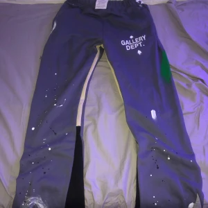 Grå mjukisbyxor från Gallery Dept. - Säljer ett par grå mjukisbyxor från Gallery Dept. med coola färgstänk och tryck. Byxorna har en avslappnad passform och är tillverkade i 100% bomull. Perfekta för en chill dag hemma eller en avslappnad utflykt.