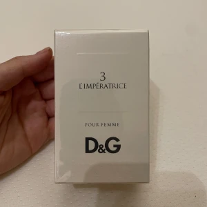 D&G 3 L'Impératrice Pour Femme - Säljer en elegant parfym från Dolce & Gabbana, 3 L'Impératrice Pour Femme. Förpackningen är vit och stilren med D&G-logotypen tydligt synlig. Perfekt för den som söker en sofistikerad doft.