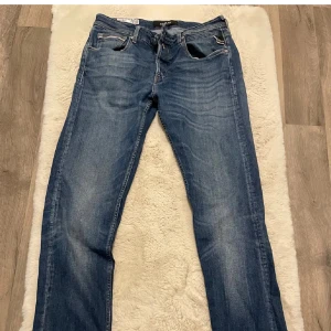 Blå jeans från Replay - Säljer ett par snygga blå jeans från Replay, modell Grover. De har en klassisk femficksdesign med dragkedja och knapp. Perfekta för en avslappnad stil.