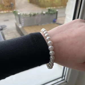 Vitt pärlarmband - Elegant vitt pärlarmband med klassiska runda pärlor. Perfekt för att ge en sofistikerad touch till din outfit. Armbandet är elastiskt och passar de flesta handleder. Större pärlor och man får båda armbanden!