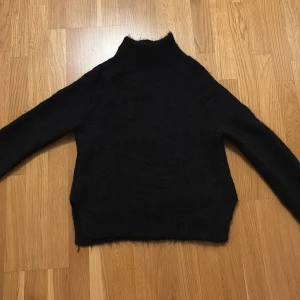 Stickad tröja  - Mysig svart polotröja från Gina Tricot i en mjuk och varm kvalitet. Perfekt för kyliga dagar med sin höga krage och långa ärmar. En stilren och enkel design som passar till det mesta.