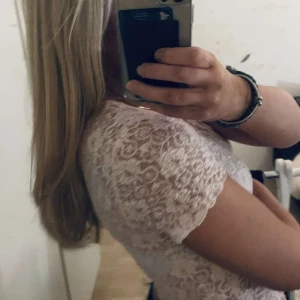 Rosa spetsblus - Säljer en söt rosa spetsblus med korta ärmar. Perfekt för en somrig look eller en elegant touch till vardagsoutfiten. Blusen har ett vackert spetsmönster som ger en romantisk känsla.